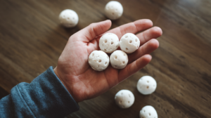 one hand holding hydroton clay balls suitable as a growth medium for hydroponic herbs